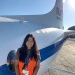 Image of NASA Ames scientist Jaden Ta wearing a safety jacket while standing in front of a NASA aircraft.