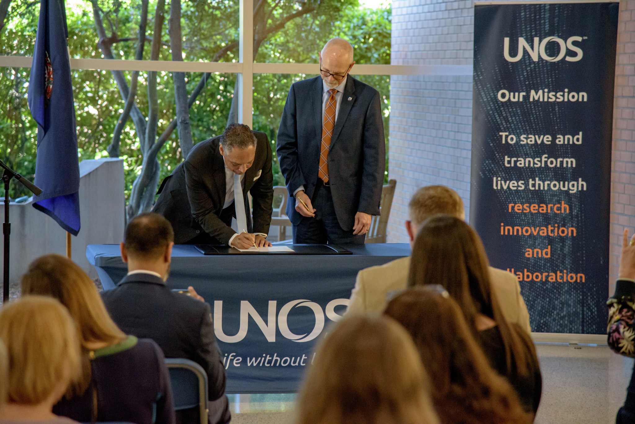 Mark Johnson, left, interim CEO of UNOS, signs his name as John Koelling, director of the Aeronautics Research Directorate at NASA's Langley Research Center, looks on.