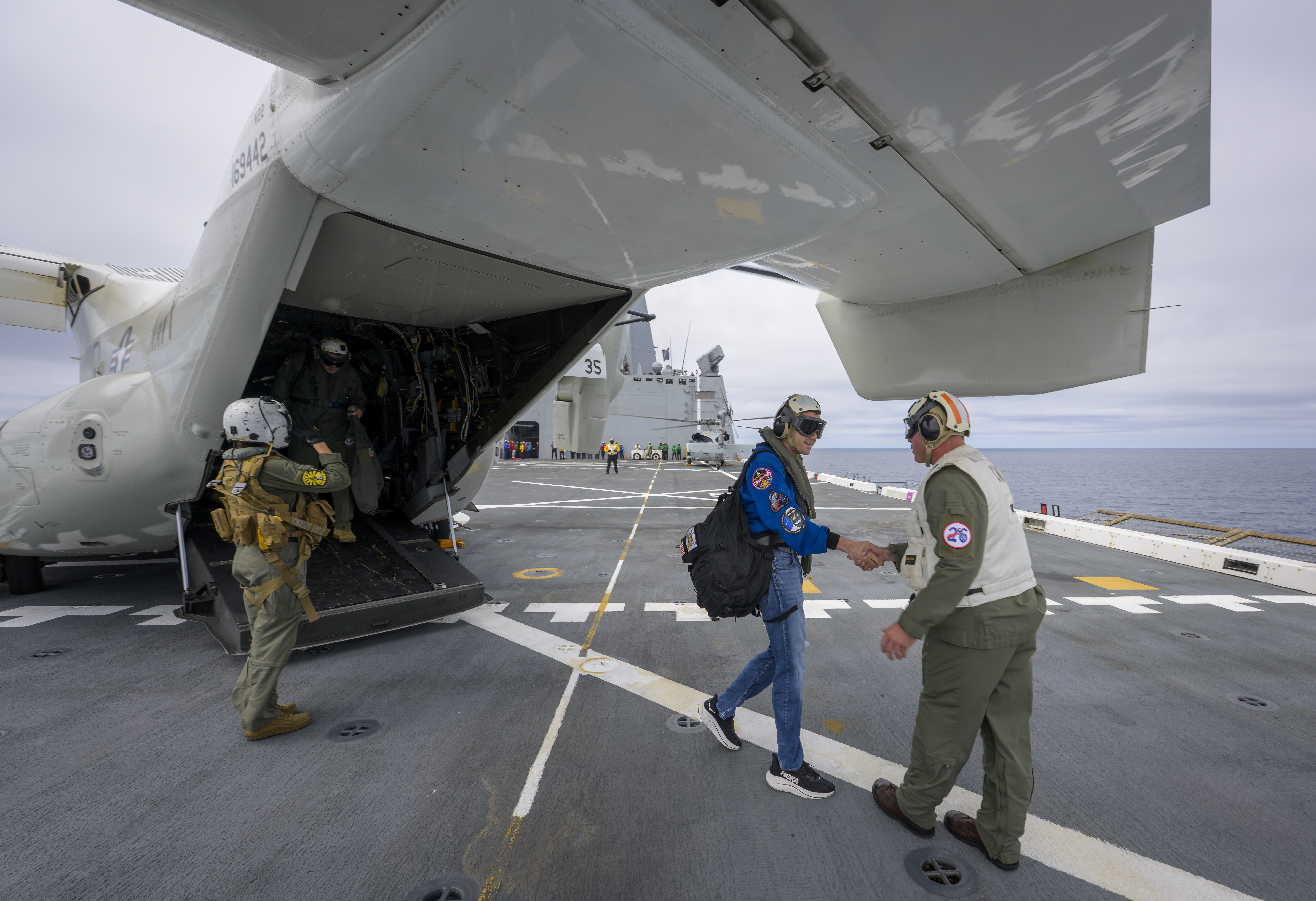 NASA Administrator Jared Isaacman, left, is greeted by Capt. Erik Kenny, commanding officer, USS John P. Murtha (LPD, after a...