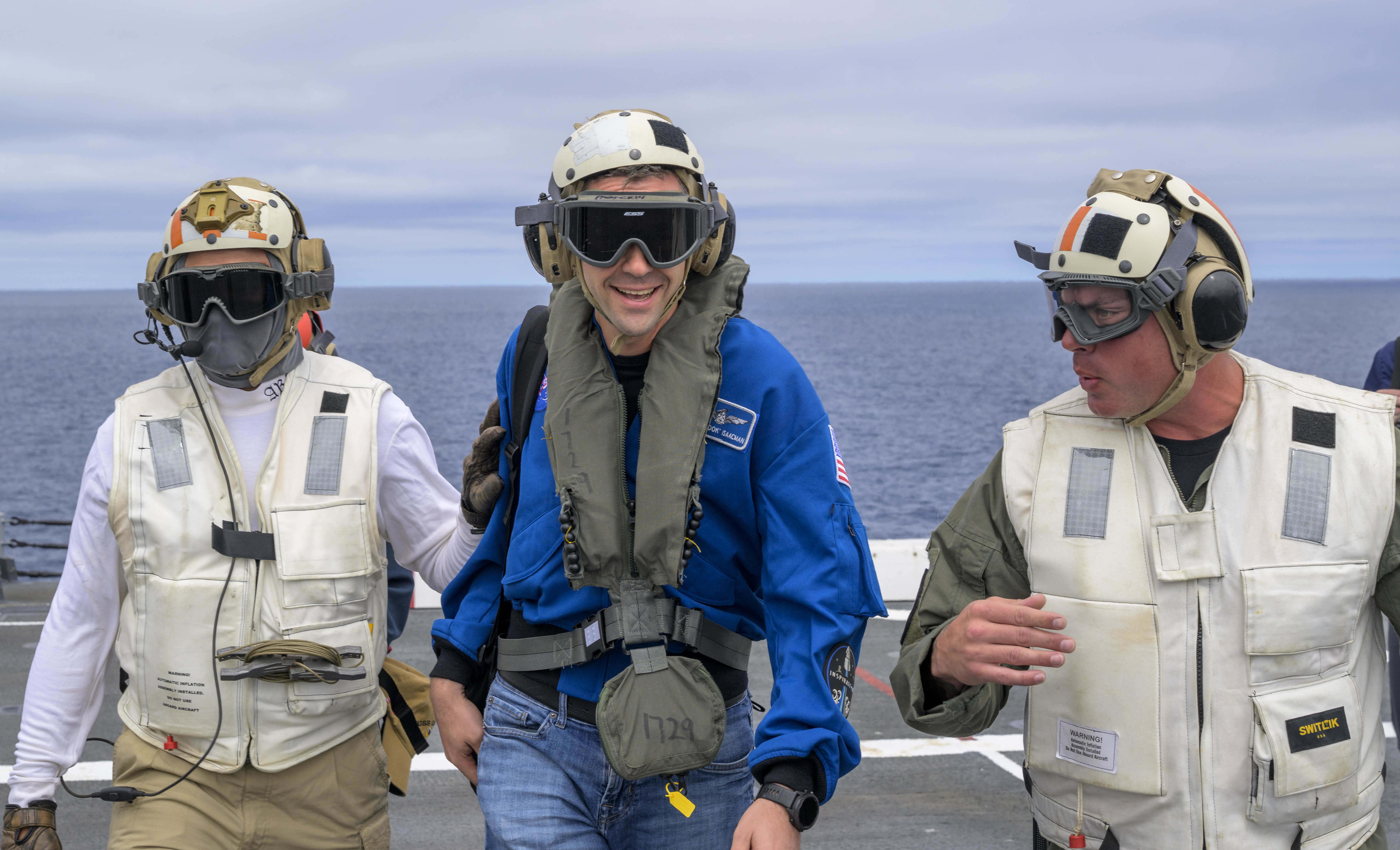 NASA Administrator Jared Isaacman, center, is greeted by Capt. Erik Kenny, commanding officer, USS John P. Murtha (LPD), right, after...