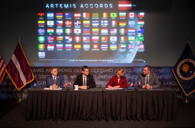 Dace Melbārde, Latvia’s Minister for Education and Science, second from right, signs the Artemis Accords, as NASA Administrator Jared Isaacman, second from left, Jacob Helberg, U.S. Under Secretary of State for Economic Affairs, left, and Jānis Beķeris, Chargé D’Affaires a.i. at the Embassy of the Republic of Latvia to the United States, right, look on Monday, April 20, 2026, at the Mary W. Jackson NASA Headquarters building in Washington. The Artemis Accords graphic of all signatory flags is behind them.