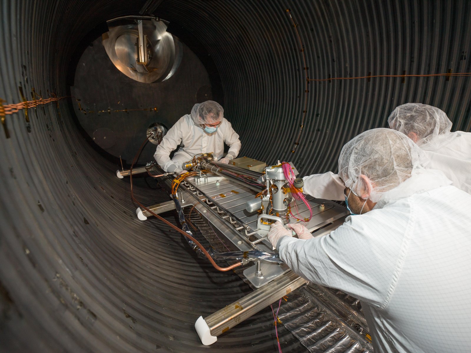 Engineers moving the COLDArm through a vacuum chamber.