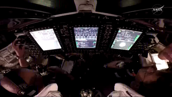 A view over the shoulders of NASA astronauts Victor Glover (left) and Reid Wiseman (right), pilot and commander, respectively, inside the Orion spacecraft as they participate in a proximity operations demonstration. This demonstration tests the spacecraft’s ability to manually maneuver relative to another spacecraft, the interim cryogenic propulsion stage, after separation, using its onboard navigation sensors and reaction control thrusters.