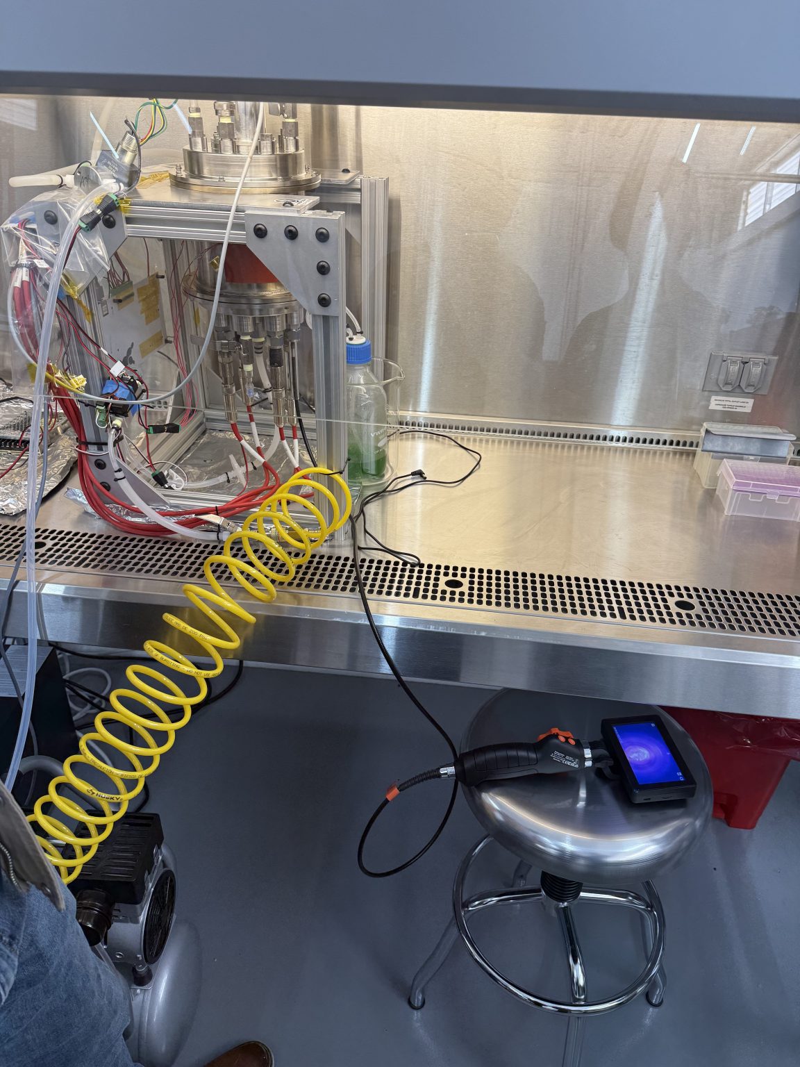 A device with a coiled yellow tube sits within an enclosed glass case.