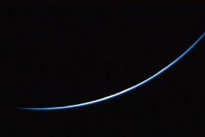 The edge of Earth is a thin line curving upward from left to right. The line is different shades of blue.