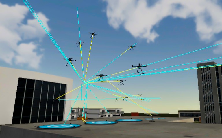 In a screengrab from a video, about a dozen drones are seen maneuvering over a city building, their paths shown with blue or yellow lines.