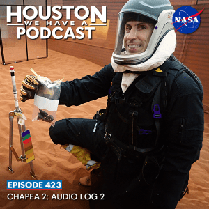 Houston We Have a Podcast Episode 423: CHAPEA 2: Audio Log 2 A member of the CHAPEA 2 crew wearing a simulated space suit poses next to a small structure on the simulated surface of Mars.
