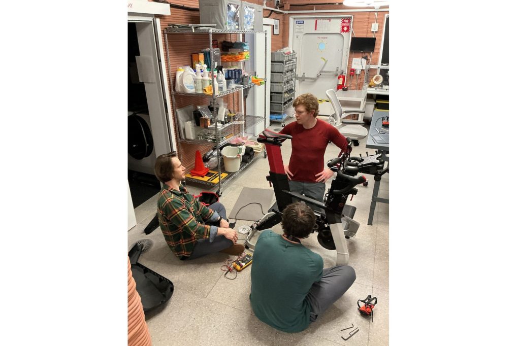 CHAPEA mission 2 crew members perform a maintenance task on their stationary bike (Clockwise from the left: Matthew Montgomery, James Spicer, and Ross Elder).