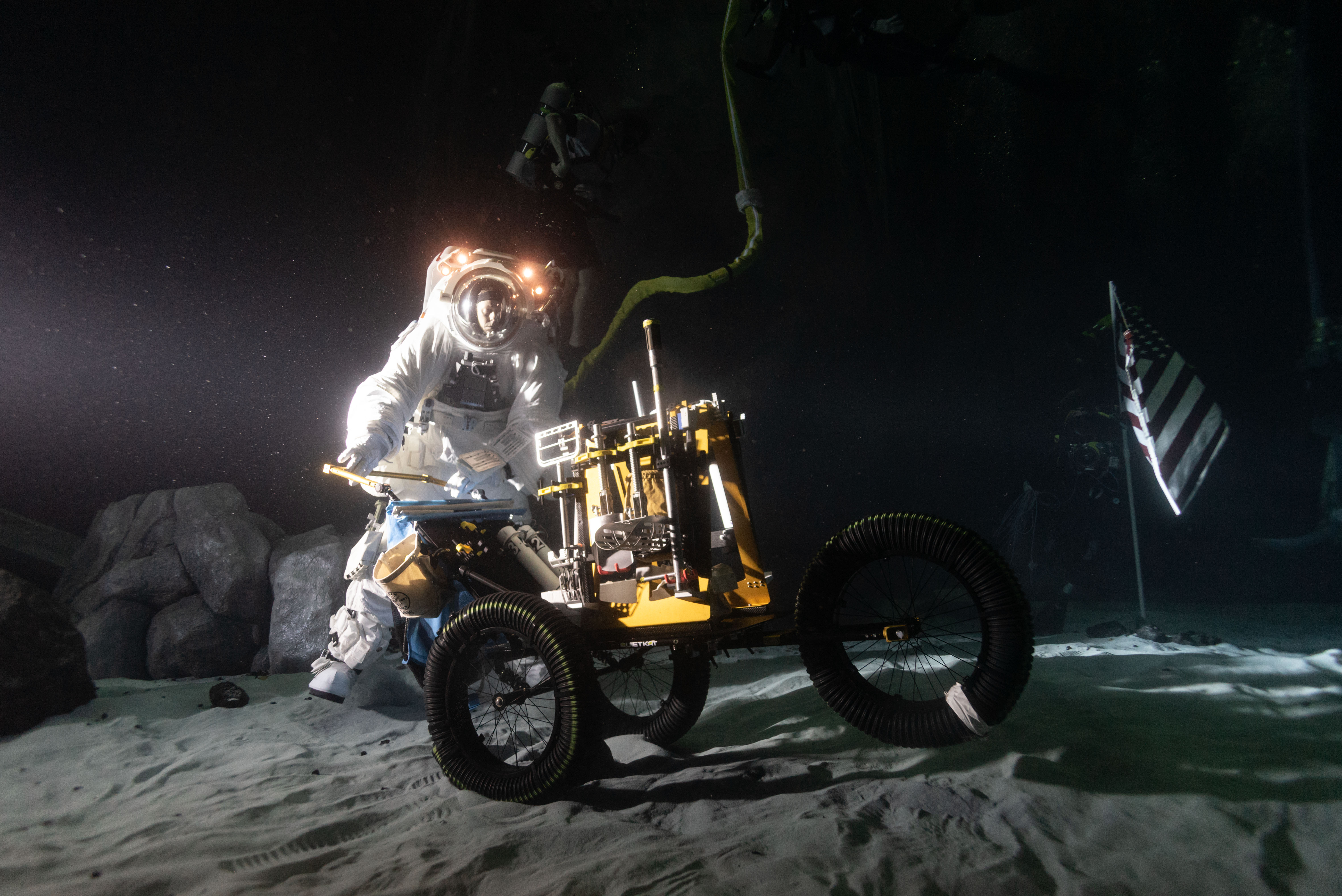 Wearing a spacesuit, Scott Wray conducts an underwater test in lunar night-like lighting at the bottom of the Neutral Buoyancy Laboratory pool.