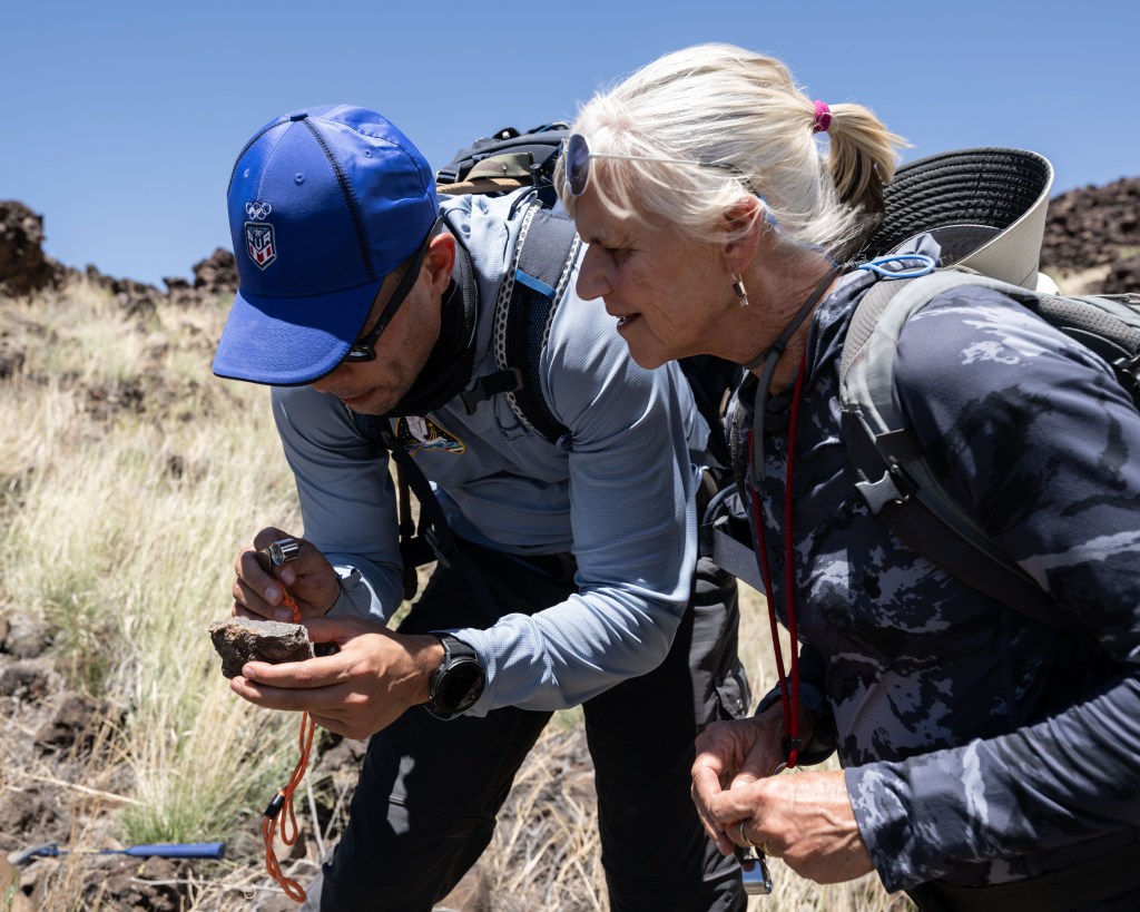 A man and a woman study a rock with small magnifying glass in the Arizona dessert.