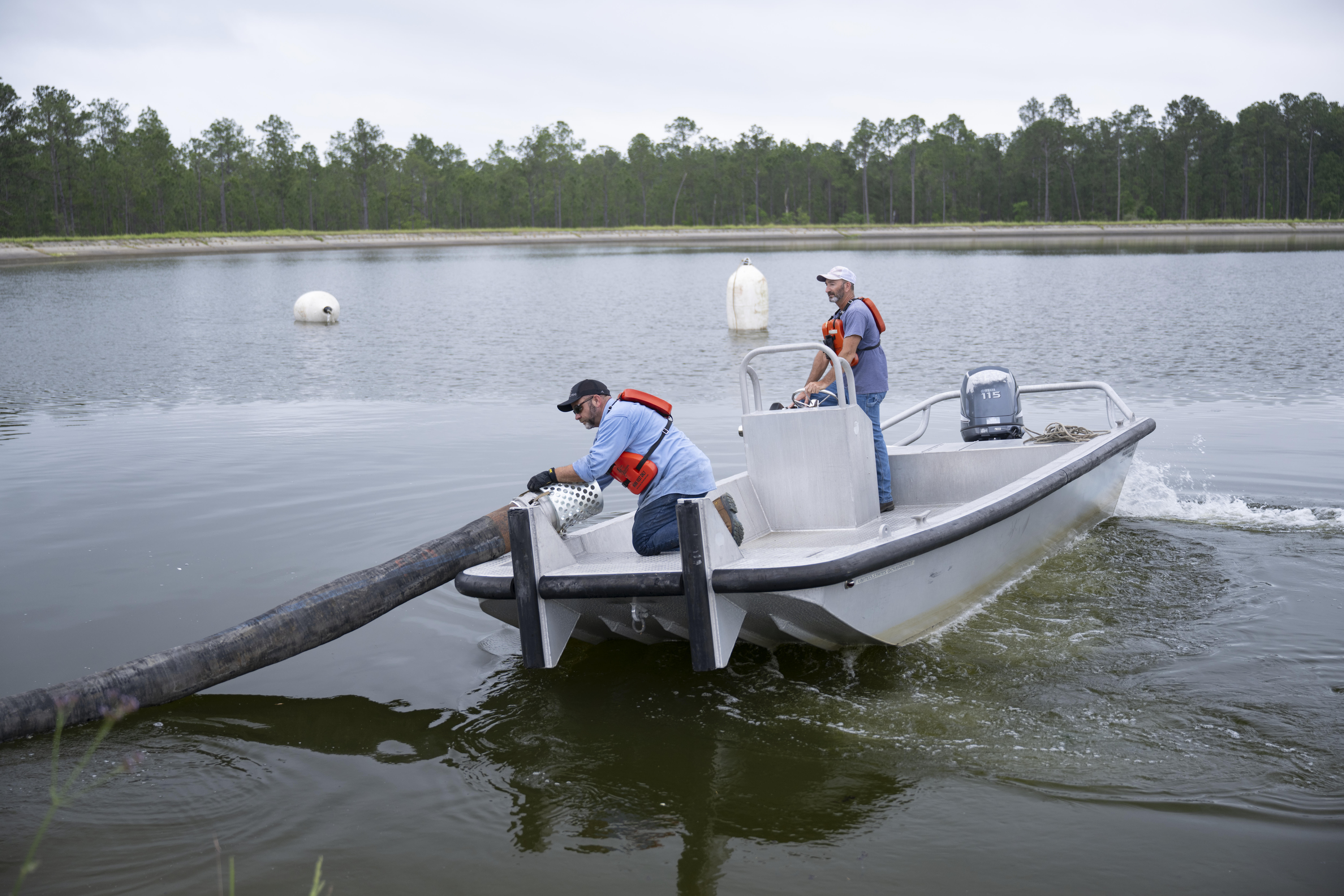 A work crew places suction piping supported by floating buoys across the reservoir surface on May 6 to prepare for pumping out water without disturbing the reservoir floor.