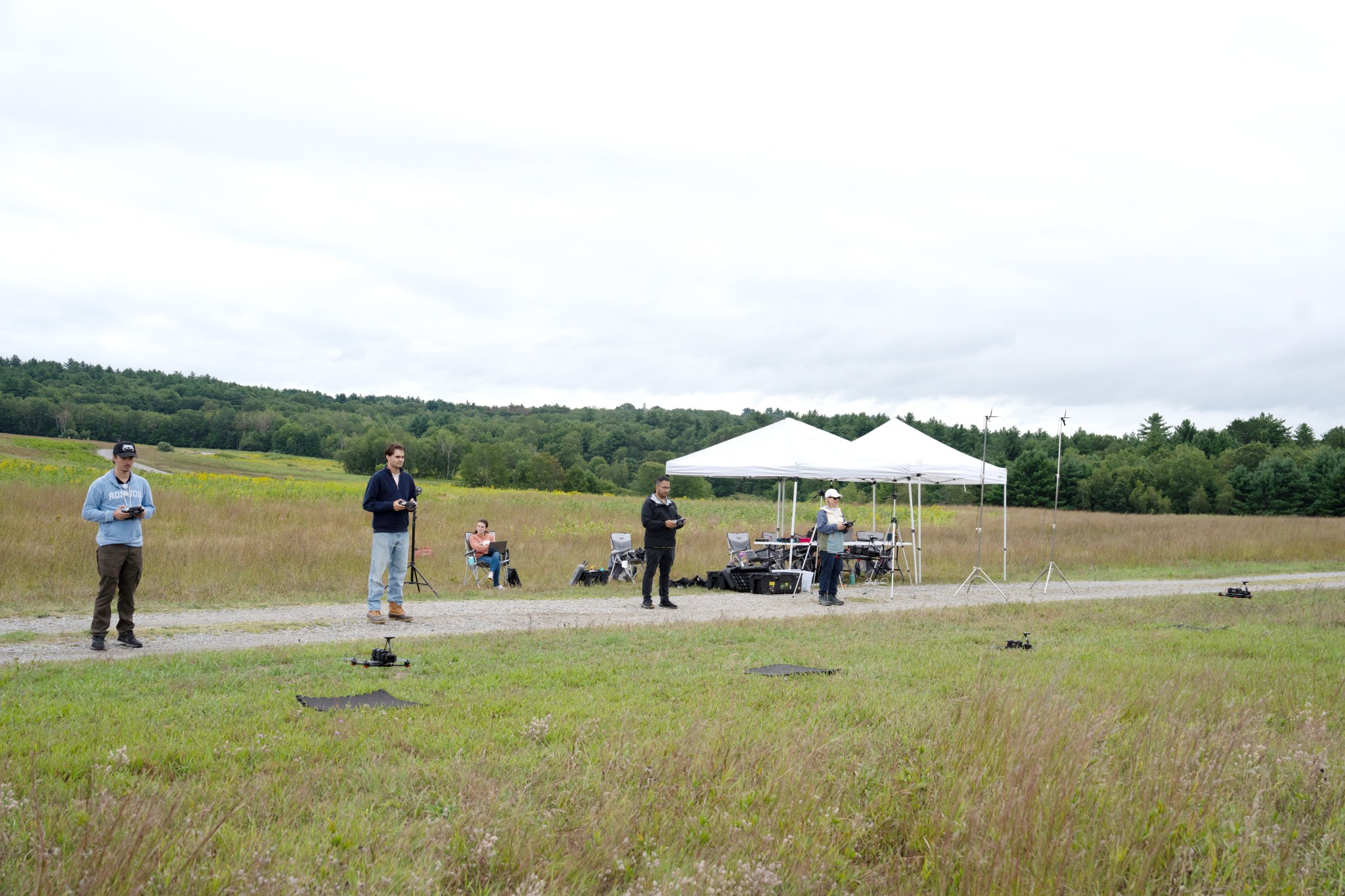 Researchers outside in a field testing drones.