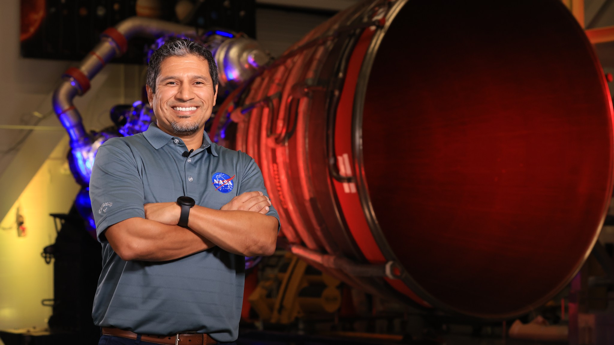 Elkin Norena, who serves as an SLS resident management officer at NASA’s Kennedy Space Center in Florida, stands in front of an RS-25 engine.
