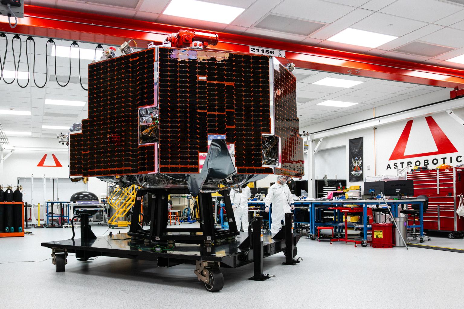 Astrobotic’s Griffin-1 lunar lander on a raised platform inside a spacecraft integration facility beneath a large Astrobotic logo mounted on the wall.