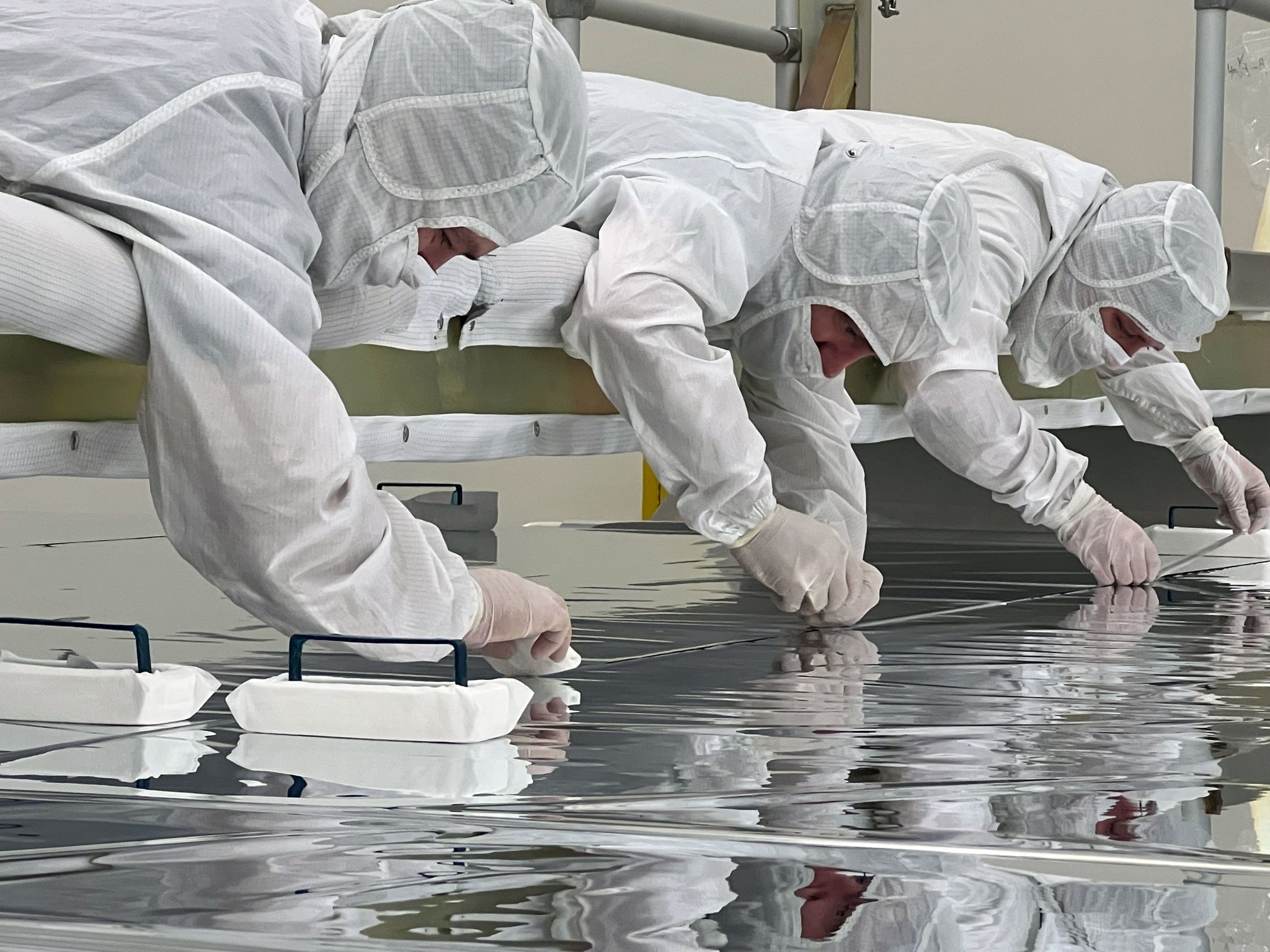 People working on the largest solar sail ever built in a clean room environment.