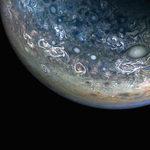 Three quarters of Jupiter can be seen in this photo; the darkness of space covers the bottom of the image. Green and blue swirls cover the planet's surface.