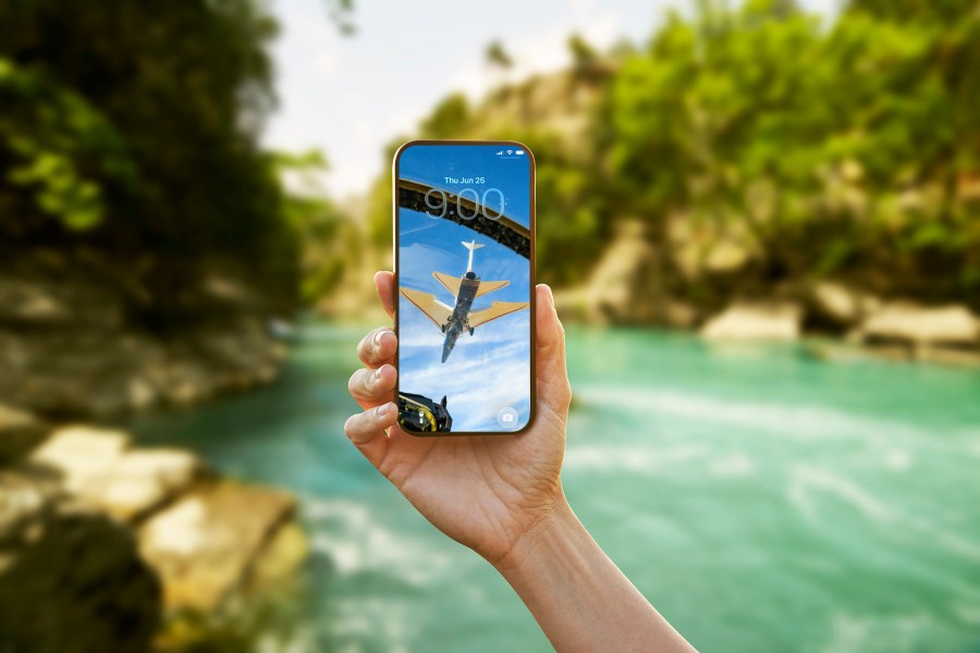 A hand holding up a cellular phone with the X-59 as the wallpaper background.