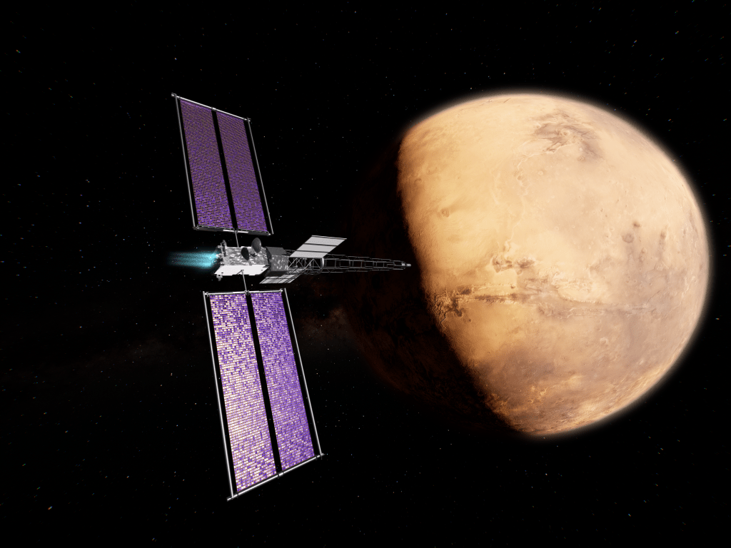 Artist’s concept of NASA’s Space Reactor-1 Freedom spacecraft flying through space near Mars. The spacecraft features a silver central body with two purple-and-white checkered solar arrays on each side. Attached to the body are two gray radiator panels and a long metal boom. Mars appears prominently on the right side of the image.