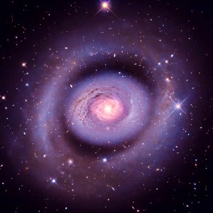 A composite image of a spiral galaxy. There is a large oval ring of dust and gas.