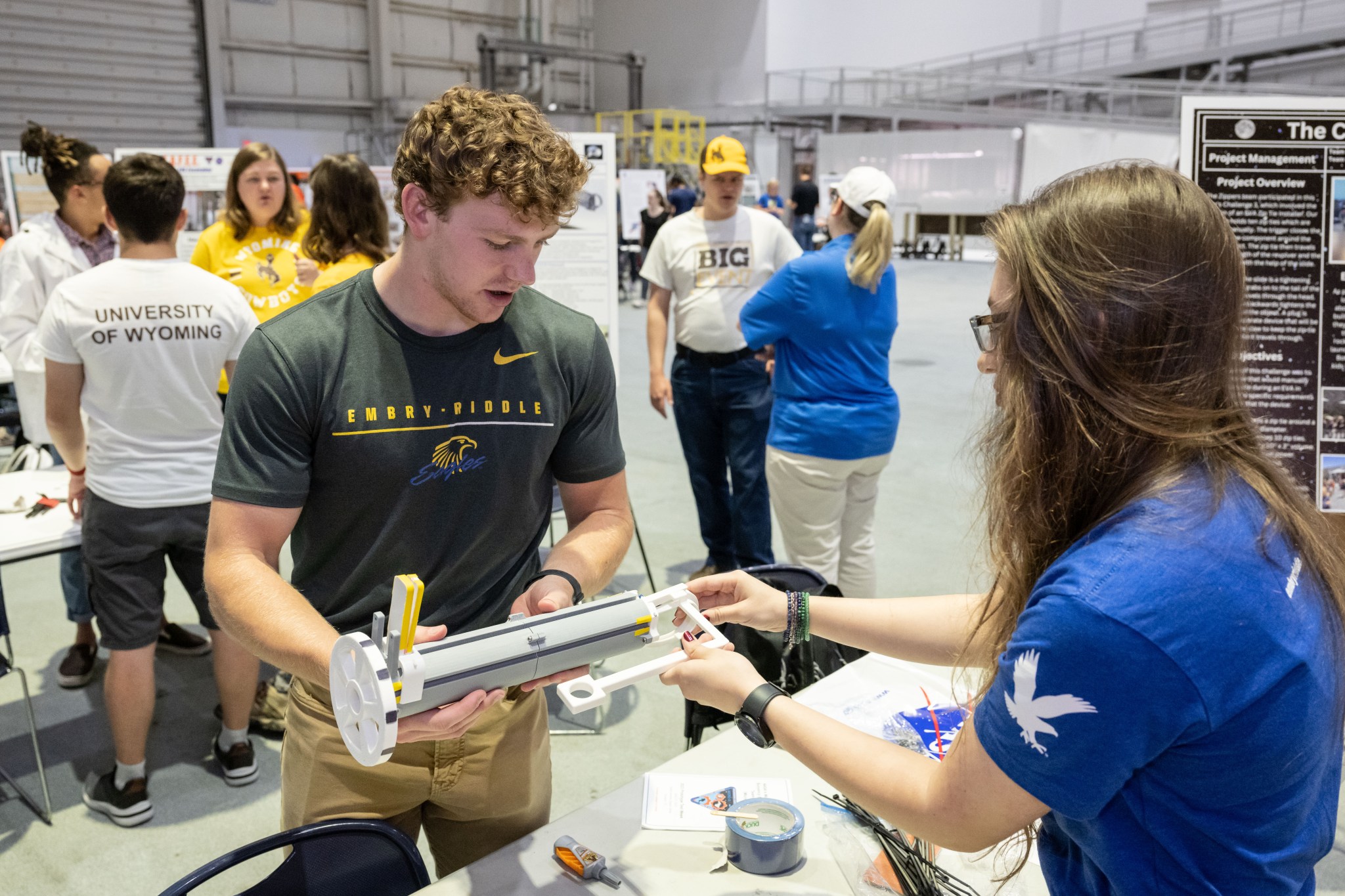 A student holding a tool they designed and explaining how it functions.