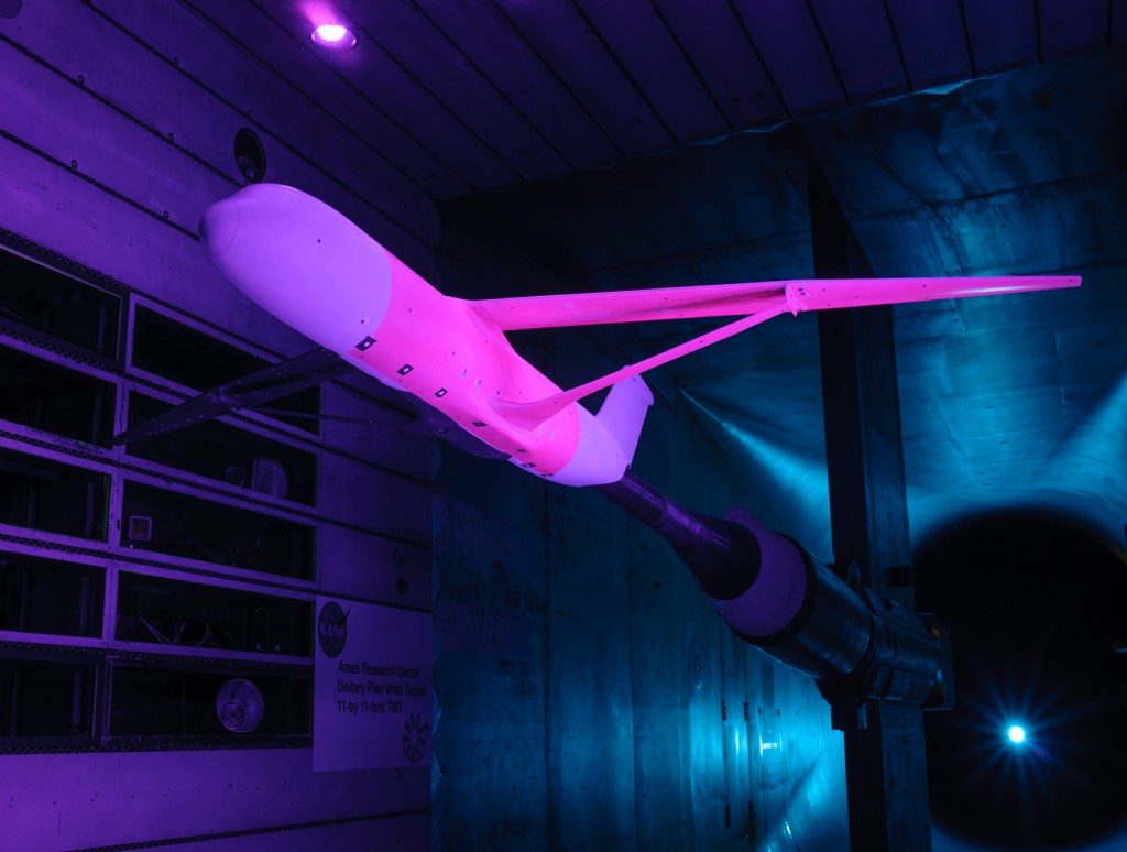 an aircraft in a testing chamber glowing pink and purple