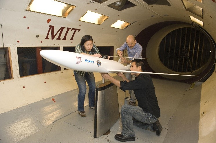 University students positioning an aircraft prototype for wind tunnel testing.