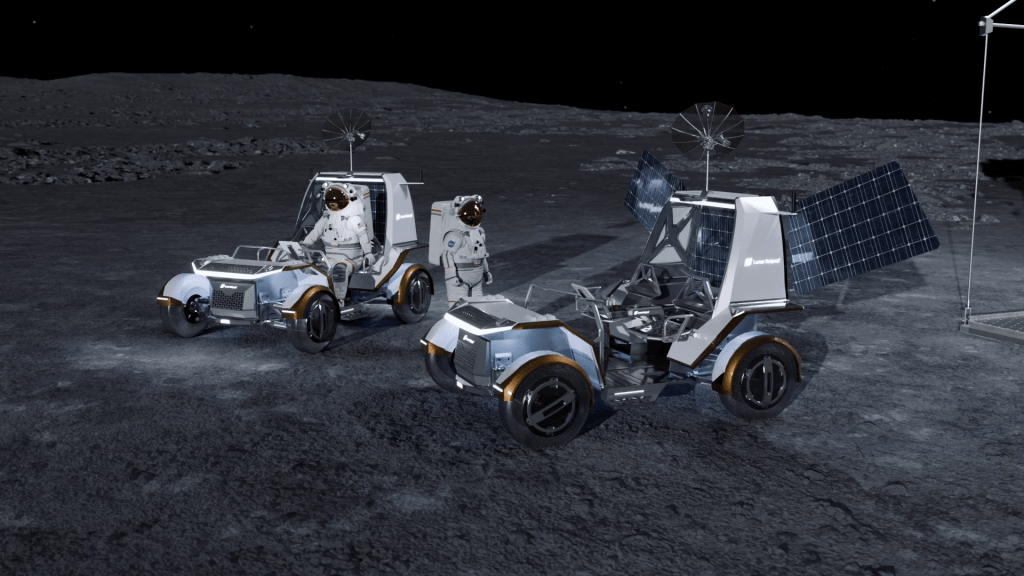 An astronaut in a white spacesuit sits inside of a white lunar terrain vehicle developed by Lunar Outpost while another astronaut in a white spacesuit stands next to another white lunar terrain vehicle developed by Lunar Outpost. The solar arrays are deployed on one of the rovers. The lunar rovers are white and gray with a copper trip around the tires.