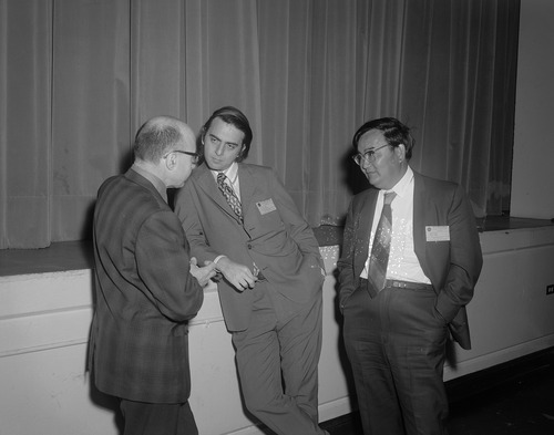 Famous scientist Dr. Carl Sagan, center, speaks with two other men at a Viking Science Symposium Biology Conference at NASA Langley.
