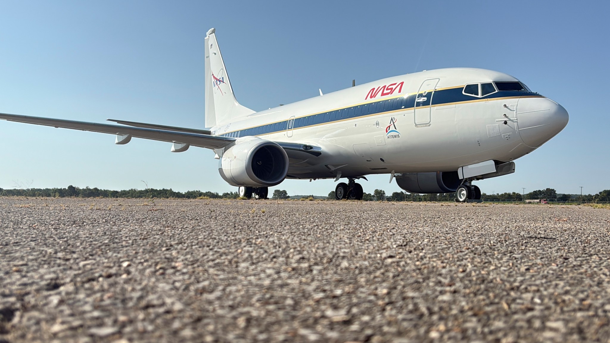 A large, white aircraft sits on a concrete surface after being painted with new NASA logos in red, white and blue.