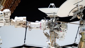 From left, Expedition 75 flight engineers Anil Menon of NASA (partially obscured and wearing the spacesuit with a red stripe on the legs) and Sophie Adenot of ESA (European Space Agency) work outside the International Space Station.