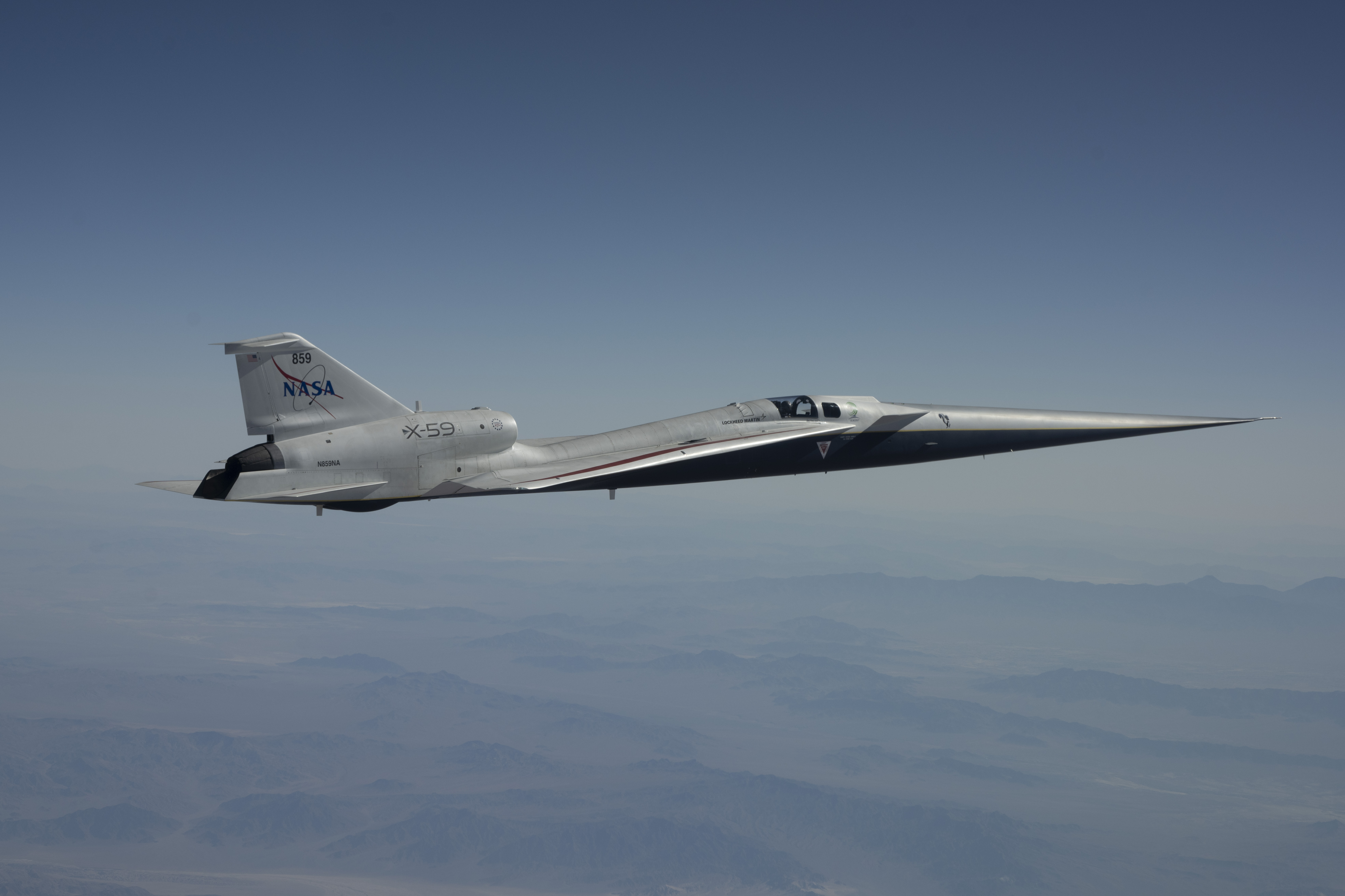 NASA’s white and blue X-59 quiet supersonic research aircraft is shown in profile against a blue sky during a test flight on June 10, 2026.