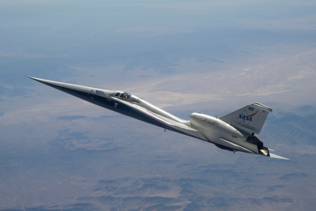 NASA’s white and blue X-59 quiet supersonic research aircraft is shown in profile against a blue sky during a test flight on June 10, 2026.