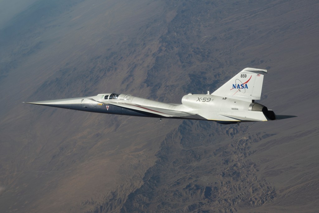 NASA’s white and blue X-59 quiet supersonic research aircraft is shown flying over the desert during a test flight on June 10, 2026.