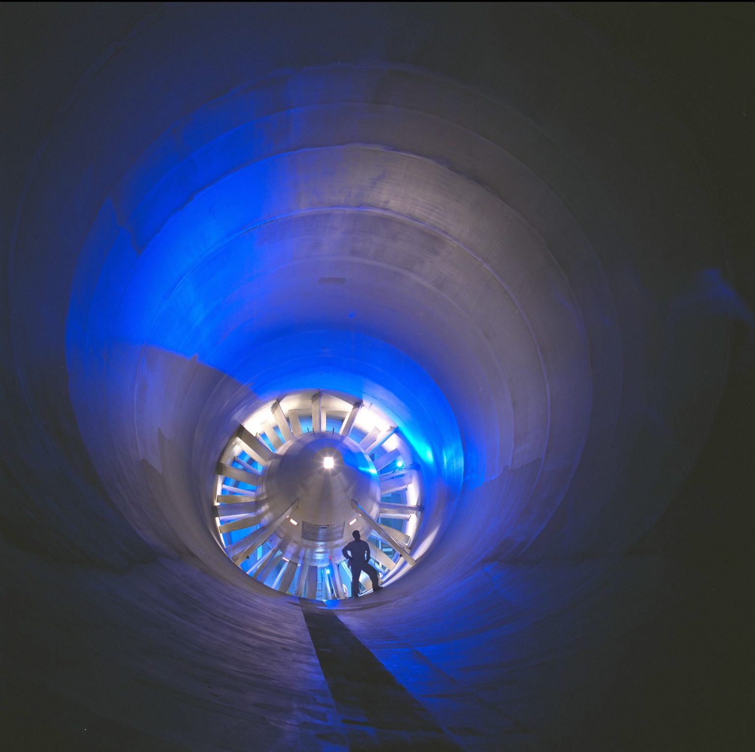 Front Door: Step Inside NASA Ames Partnerships; a person standing in front a wind tunnel turbine with dramatic blue lighting