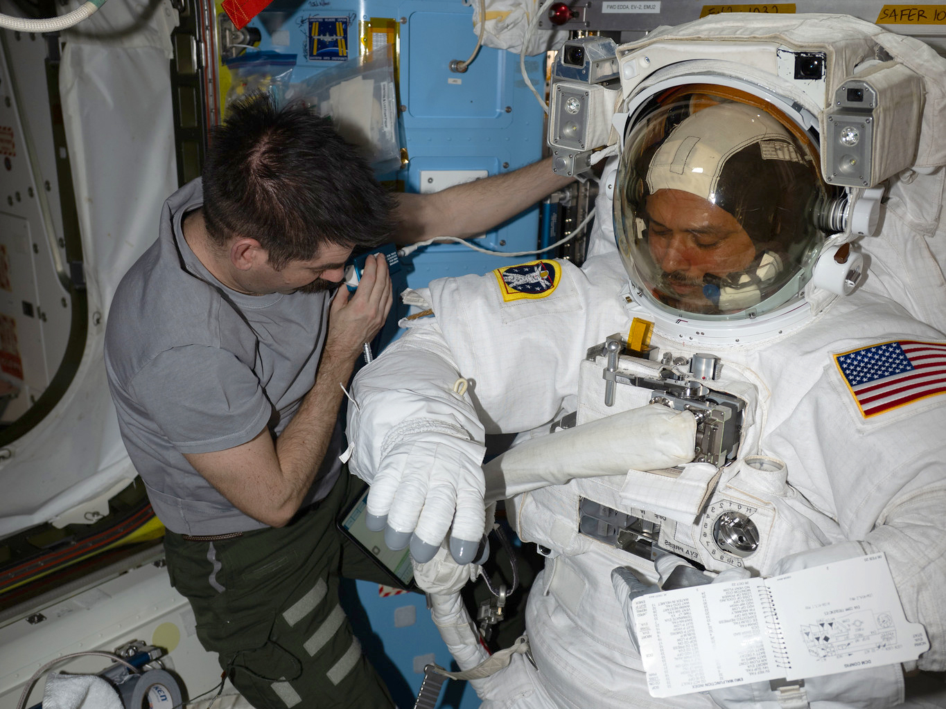 Expedition 75 flight engineer Jack Hathaway assists Expedition 75 flight engineer Anil Menon, both NASA astronauts, inside the Quest airlock as he tried on a spacesuit to verify its comfort, mobility, and functionality. Menon was conducting an on-orbit fit verification of the suit before conducting his first spacewalk outside of the International Space Station.
