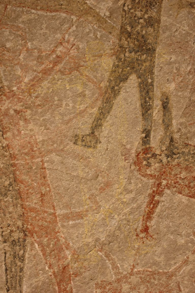 A wall with a series of faded humanoid figures painted on it.