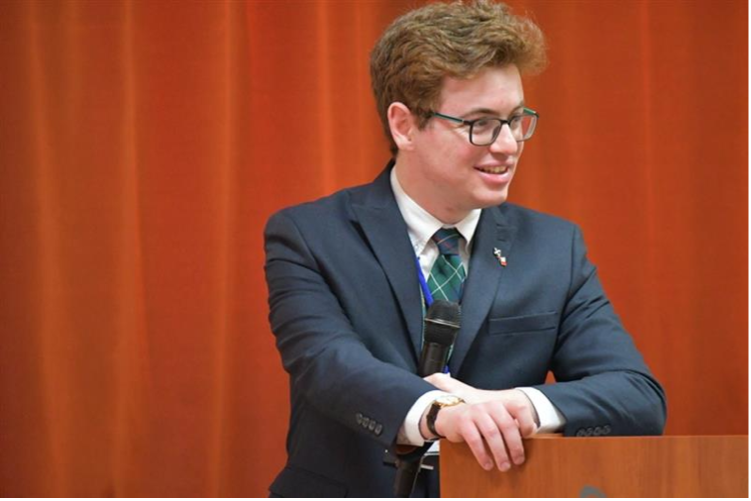 Image of Ames Research Center Astrophysics Researcher Duncan Mifsud, standing in a suit at a lectern.