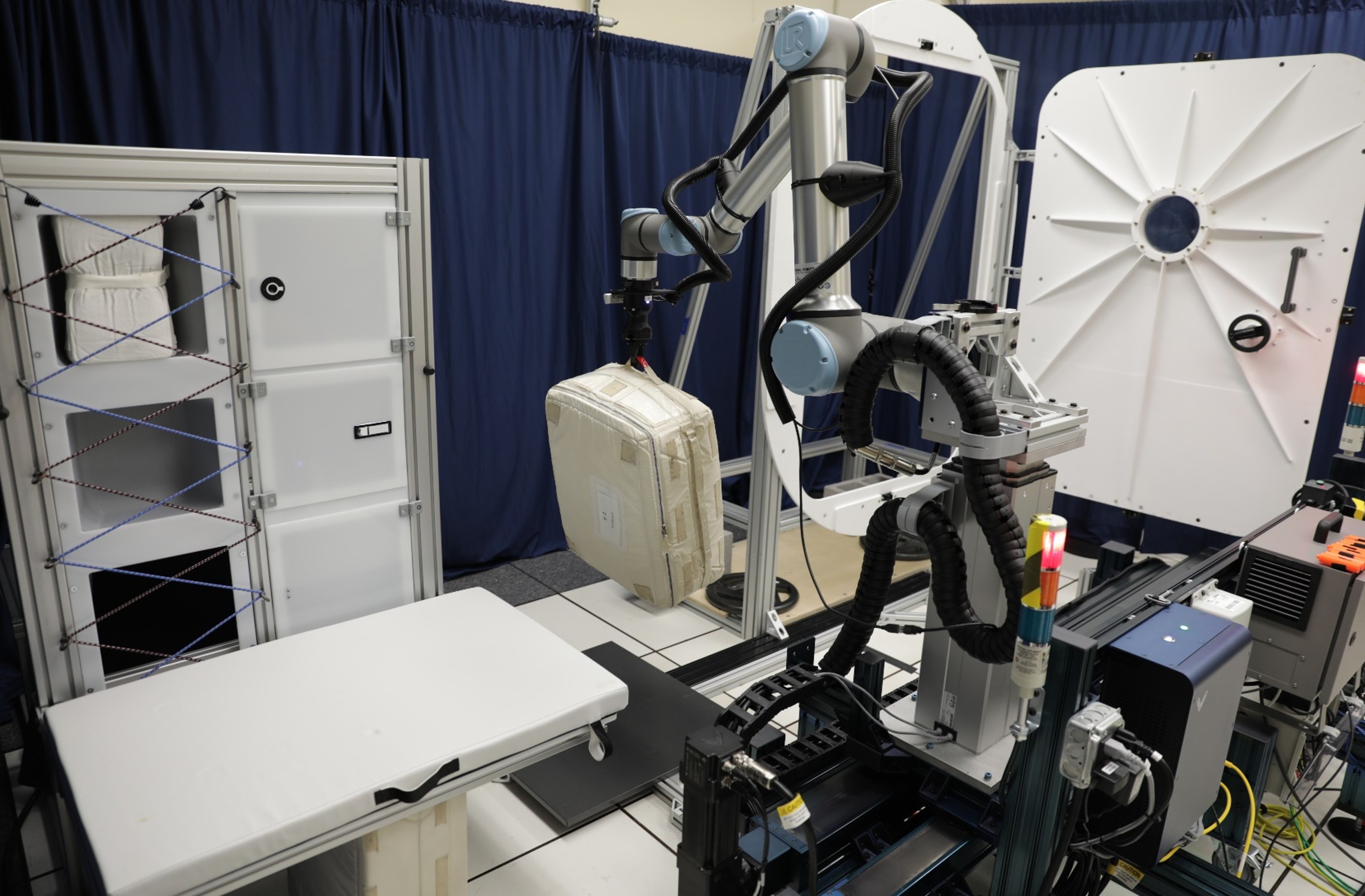 Robotic system components are shown in a lab setting, with blue drapery in the background.