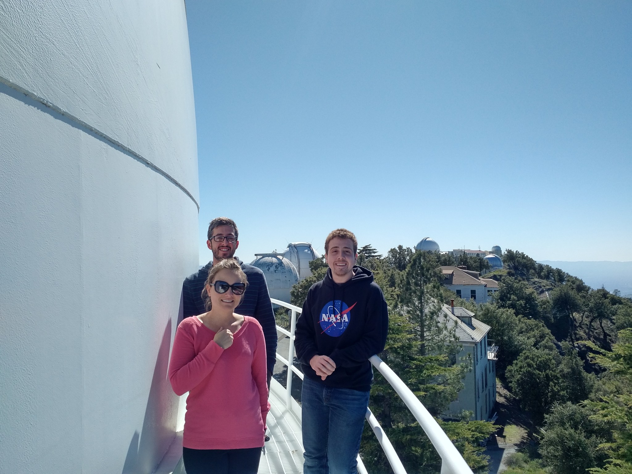 Richard Spolzino stands with his research adviser and a fellow grad student on an outdoor walkway at Lick Observatory, hills visible in the distance.