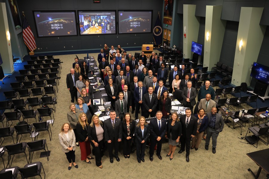 A group of people pose for a photo in a large conference room.