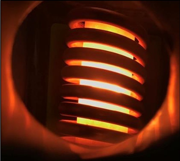 The image shows a glowing orange heating coil seen through a round opening, with the tightly wound metal spirals illuminated by bright light from inside the device.