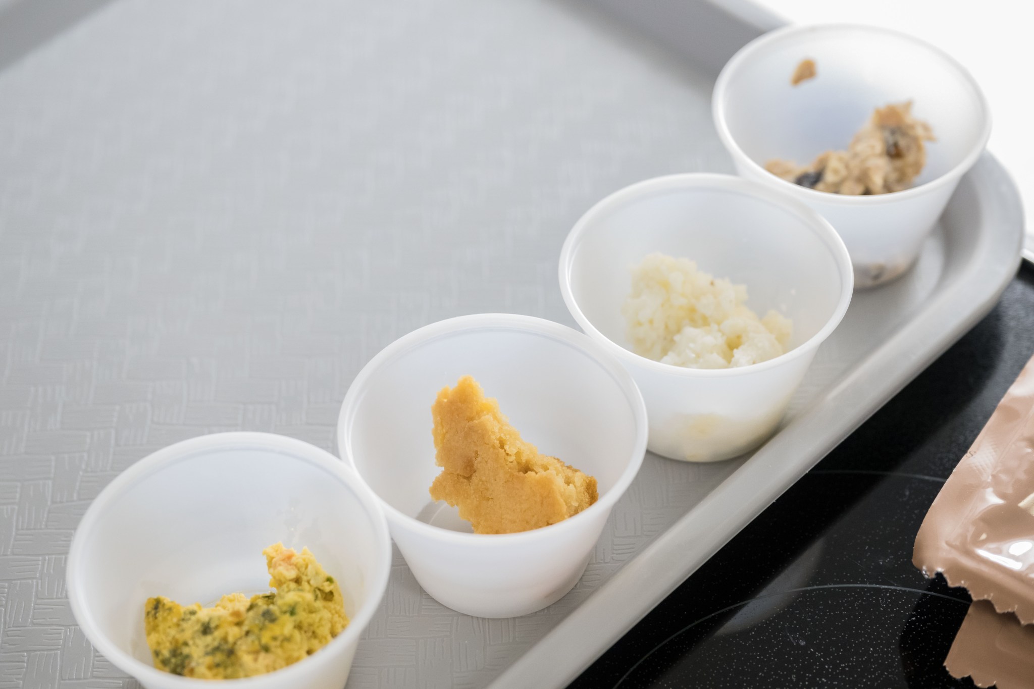 Four cups are on display with pieces of food the Artemis III crew is tasting.