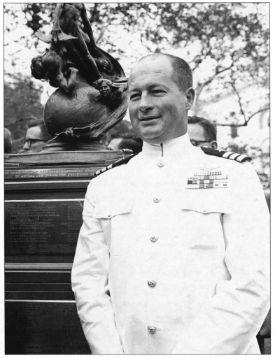 Photo of Commander Forrest S. Petersen, USN, standing beside the 1961 Collier Trophy.