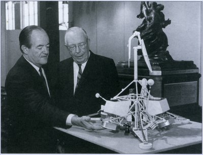 Photo of Hyland and Vice President Humphrey examining a model of Surveyor.