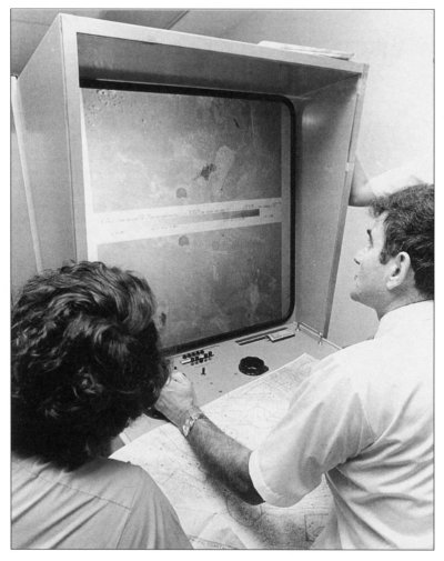 Photo of two people examining a Landsat photo on a special Machine.