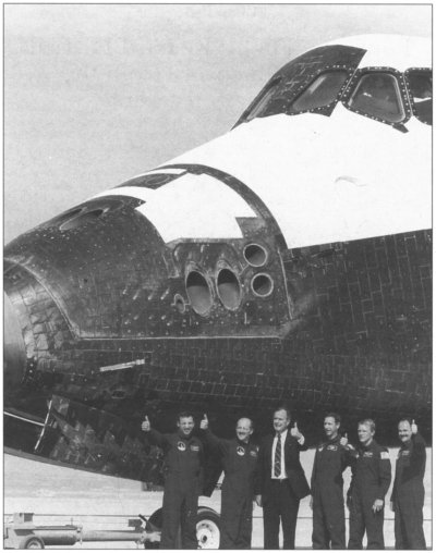 Photo shows President Bush giving thumbs-up with astronauts under shuttle Discovery.