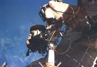 Onufriyenko and Mir-21 flight engineer Yury Usachev (blue stripe on EMU) work to install the truss on the module.