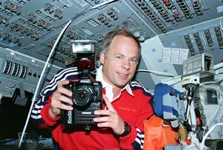 Solovyev in Shuttle's flight deck with camera