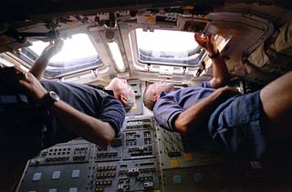 STS-79 mission commander William Readdy (left) and pilot Terry Wilcutt look out of the sun-lit aft flight deck overhead windows.
