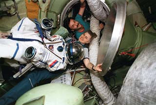 Astronaut Shannon Lucid floats with her Russian pressure suit in the Mir space station central node. She is joined by Mir-22 flight engineer Alexander Kaleri. 